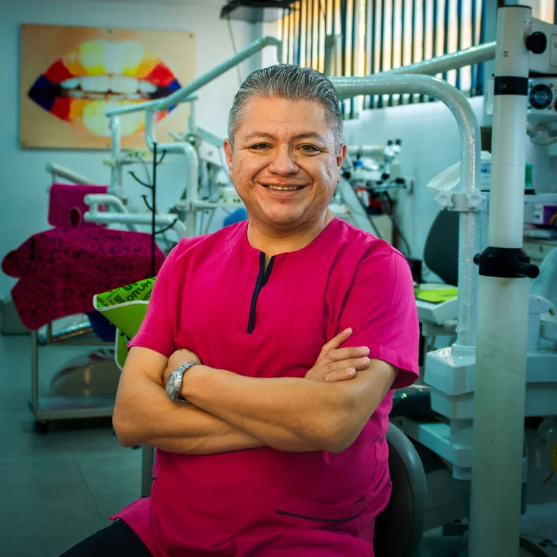 El Dr. Arturo Ramírez Tapia sonriendo en su consultorio, junto al microscopio dental
