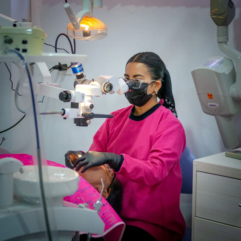 Especialista del equipo Swiss Dental trabajando con microscopio de precisión